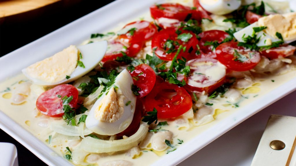 Piatto di carpaccio con pomodorini, uova sode e scaglie di formaggio