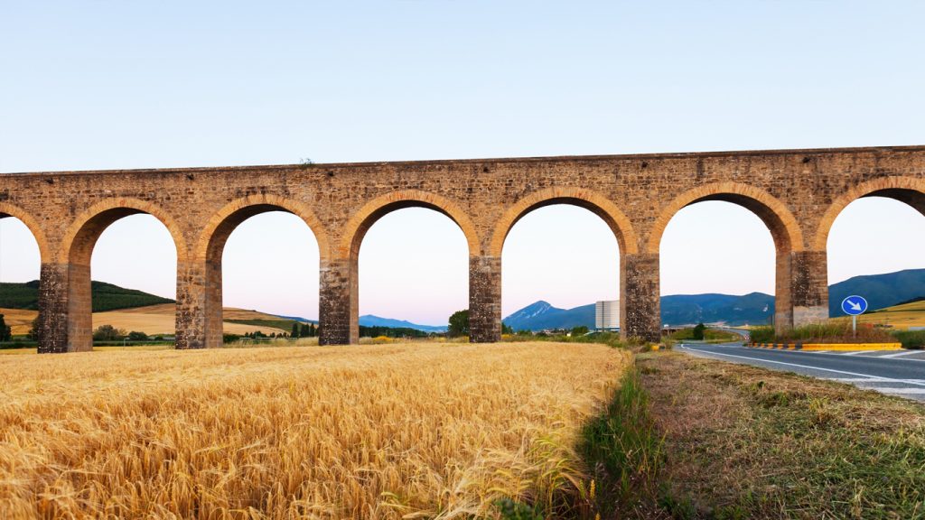 Acquedotto ad archi accanto a un campo di grano dorato