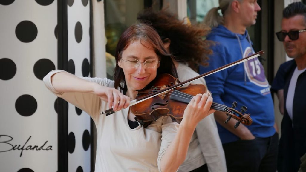 Violinista che suona per strada accanto a una parete a pois