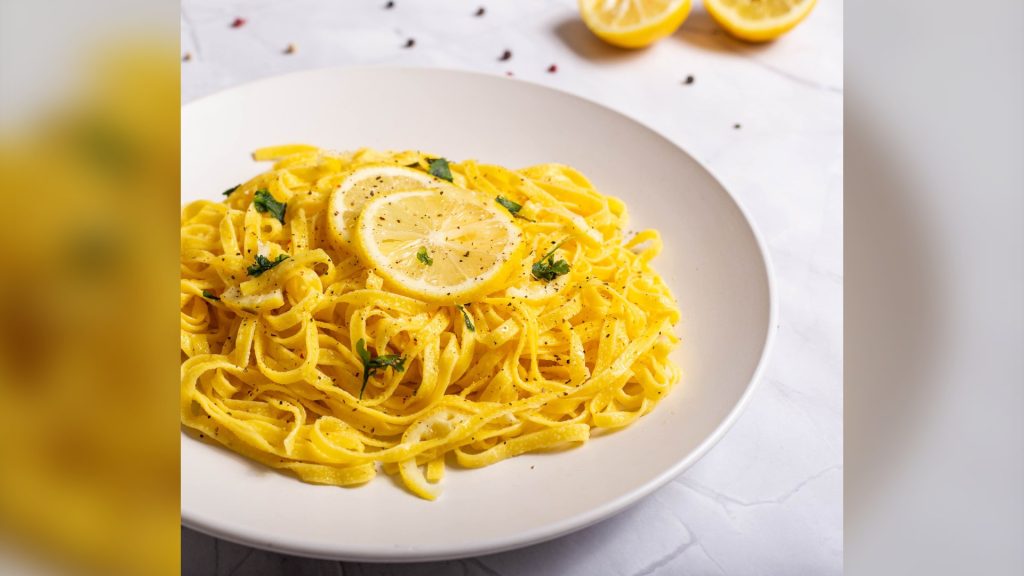 Tagliolini al limone in un piatto bianco con fette di limone